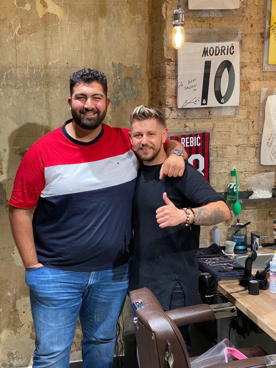 Faisal Kawusi mit einem Stylisten vor der Boki-Wand im Salon